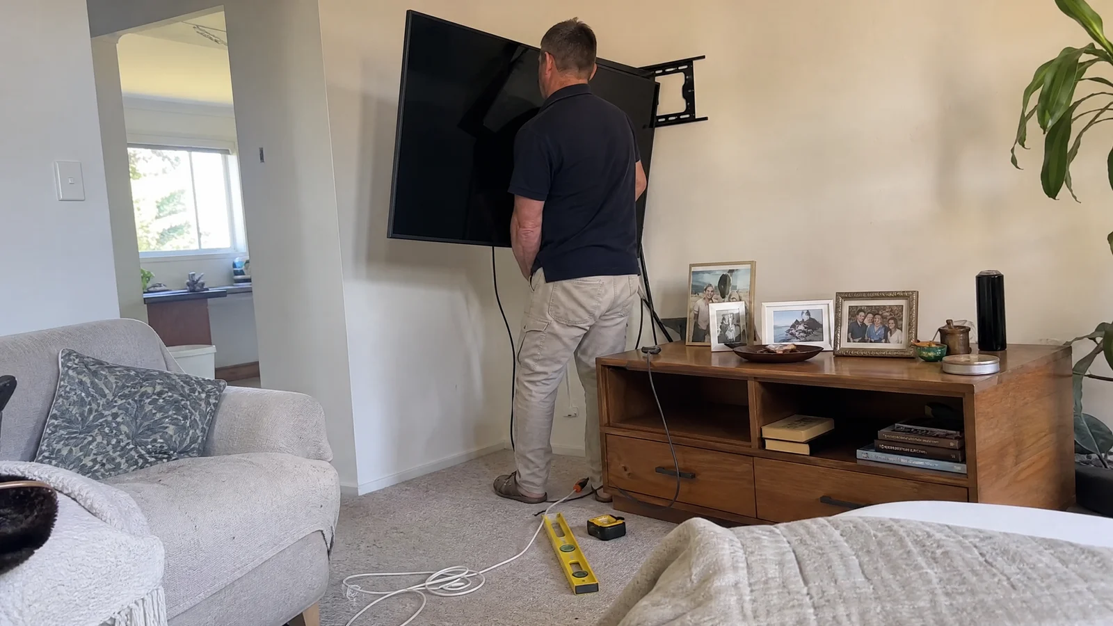 Handyman lifting a television onto a wall bracket in a Canberra lounge room